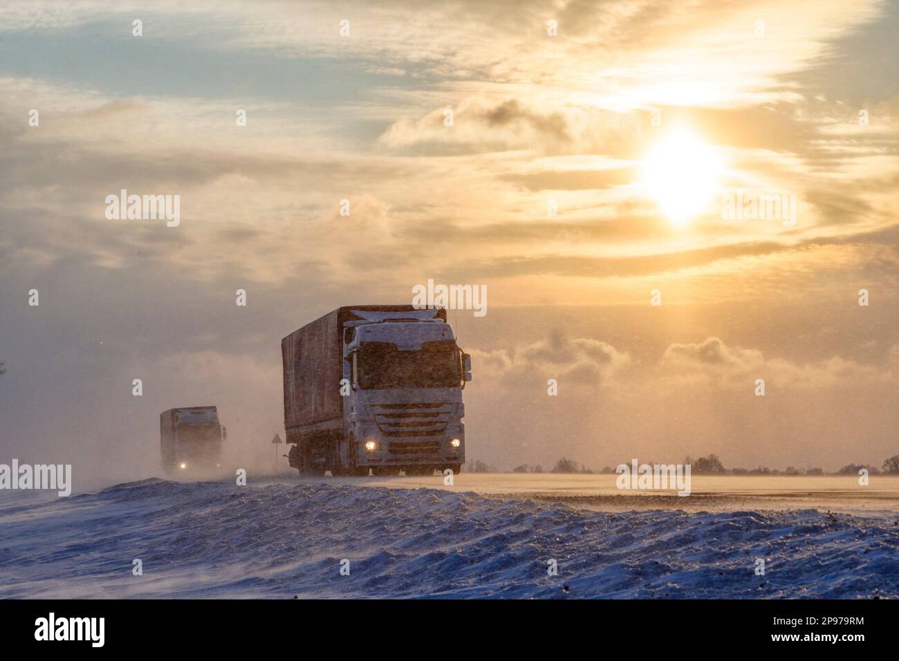 Al tramonto, il carrello sta guidando su una strada innevata. Tempesta di neve. Foto Stock