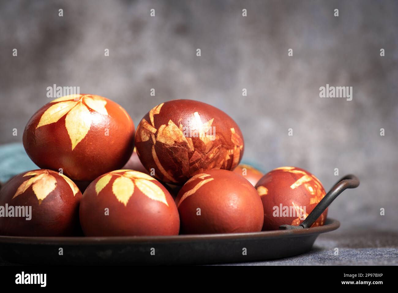 Primo piano delle uova di Pasqua tinte con bucce di cipolla con un motivo di erbe fresche in un cestino di vimini Foto Stock