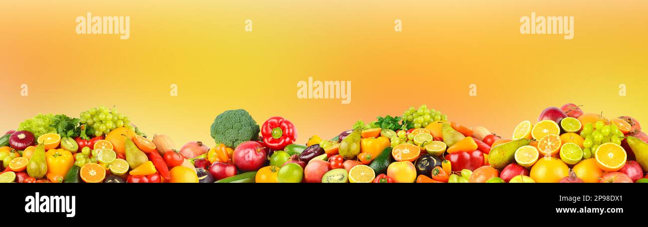Ampia raccolta di frutta, verdura e frutti di bosco su sfondo arancione sfocato. Foto Stock