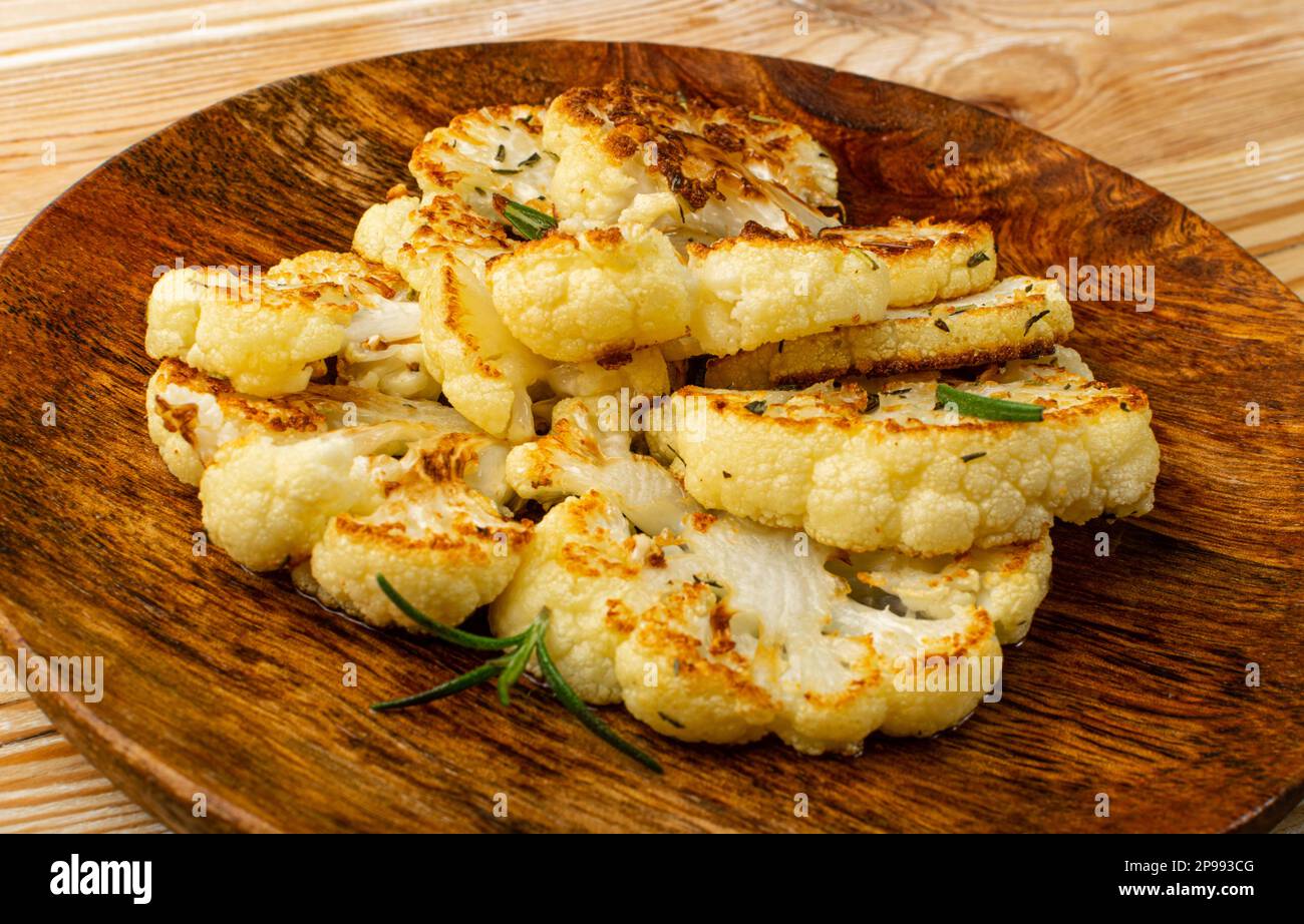 Fette di cavolfiore fritte su piatto di legno, bistecche di cavolfiore al forno, bistecca di cavolo arrosto con Closeup alle erbe Foto Stock
