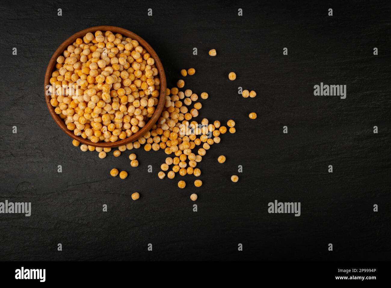 Piselli gialli secchi su fondo nero, pile di piselli interi, legume grezzo, fonte proteica, cibo vegano sano, Piselli gialli secchi sparsi su sfondo bianco Foto Stock