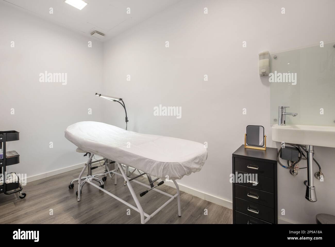 Cabine individuali nella sala massaggi con letti per l'applicazione di trattamenti con potenti lampade a doppio LED, lavelli in porcellana e cassetti in metallo Foto Stock