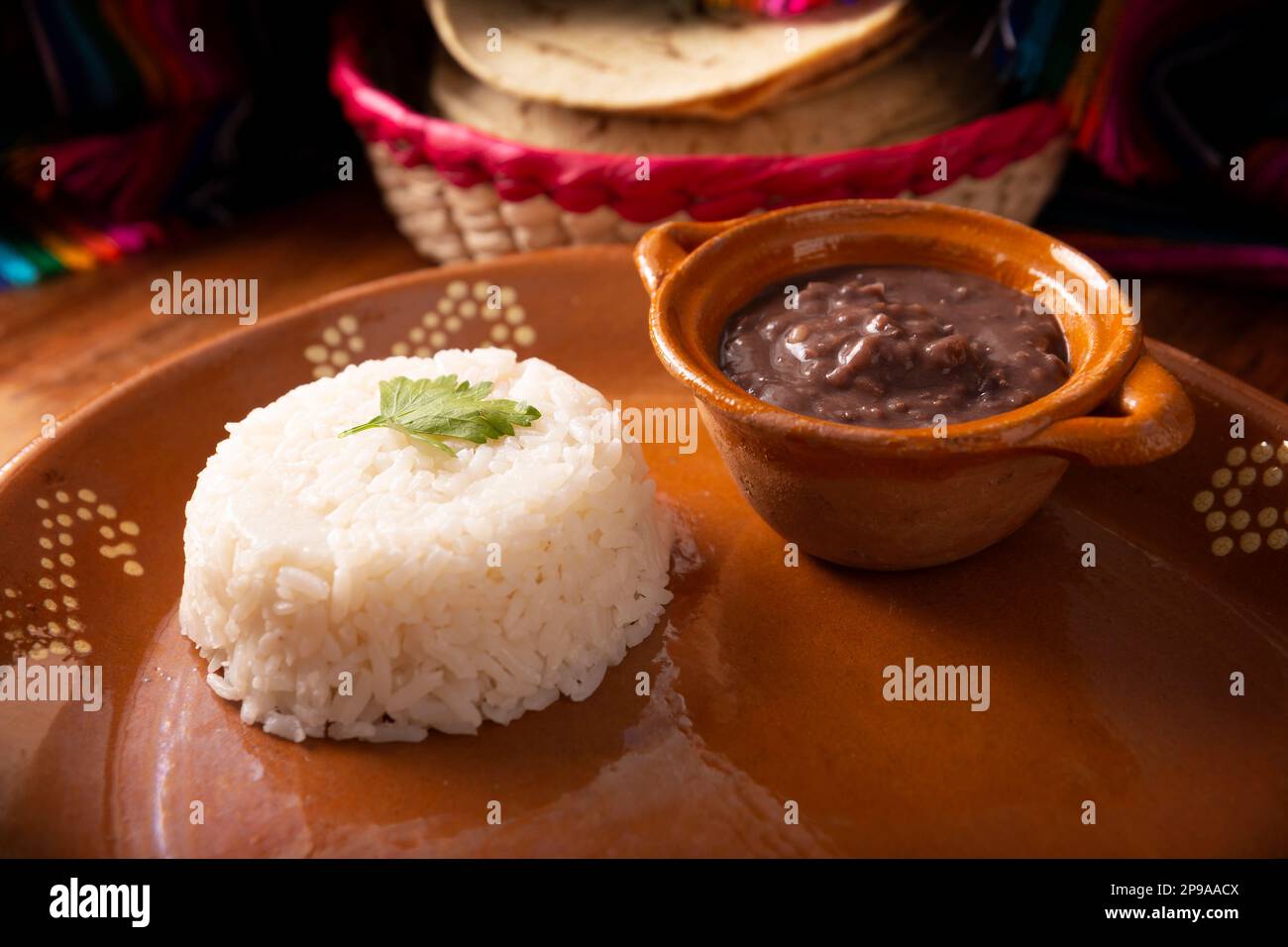 Fagioli e riso serviti in un piatto di argilla artigianale in stile messicano. Cibo molto popolare in America Latina e ampiamente utilizzato come ingrediente principale o accompagnamento Foto Stock