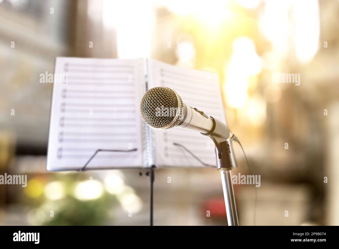Concetto con background musicale di interpretazione di canzoni religiose con microfono e musica stand in chiesa. Vista frontale. Foto Stock