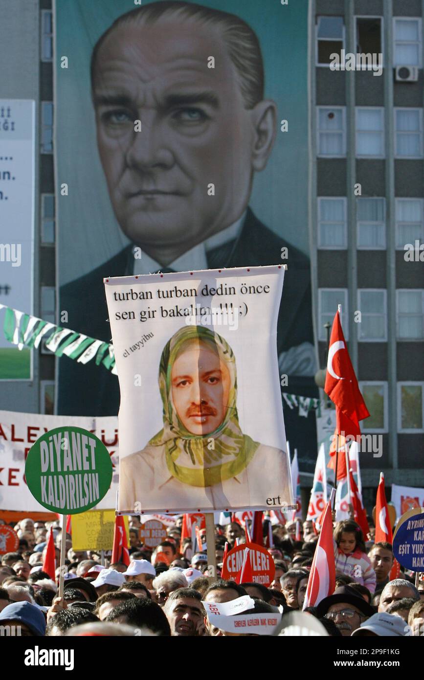 Tens of thousands of followers of Turkey's Alevi branch of Islam, holding Turkish flags with modern Turkey's founder Kemal Ataturk, rally in the capital Ankara, Turkey, Sunday, Nov. 9, 2008 to demand equal religious rights. A demonstrator holds a poster of Prime Minister Tayyip Erdogan wearing an Islamic-style headscarf with a poster of Ataturk in the background and reading:" You have been insisting on the headscarf, let's see you wear it first! " (AP Photo/Burhan Ozbilici) Foto Stock