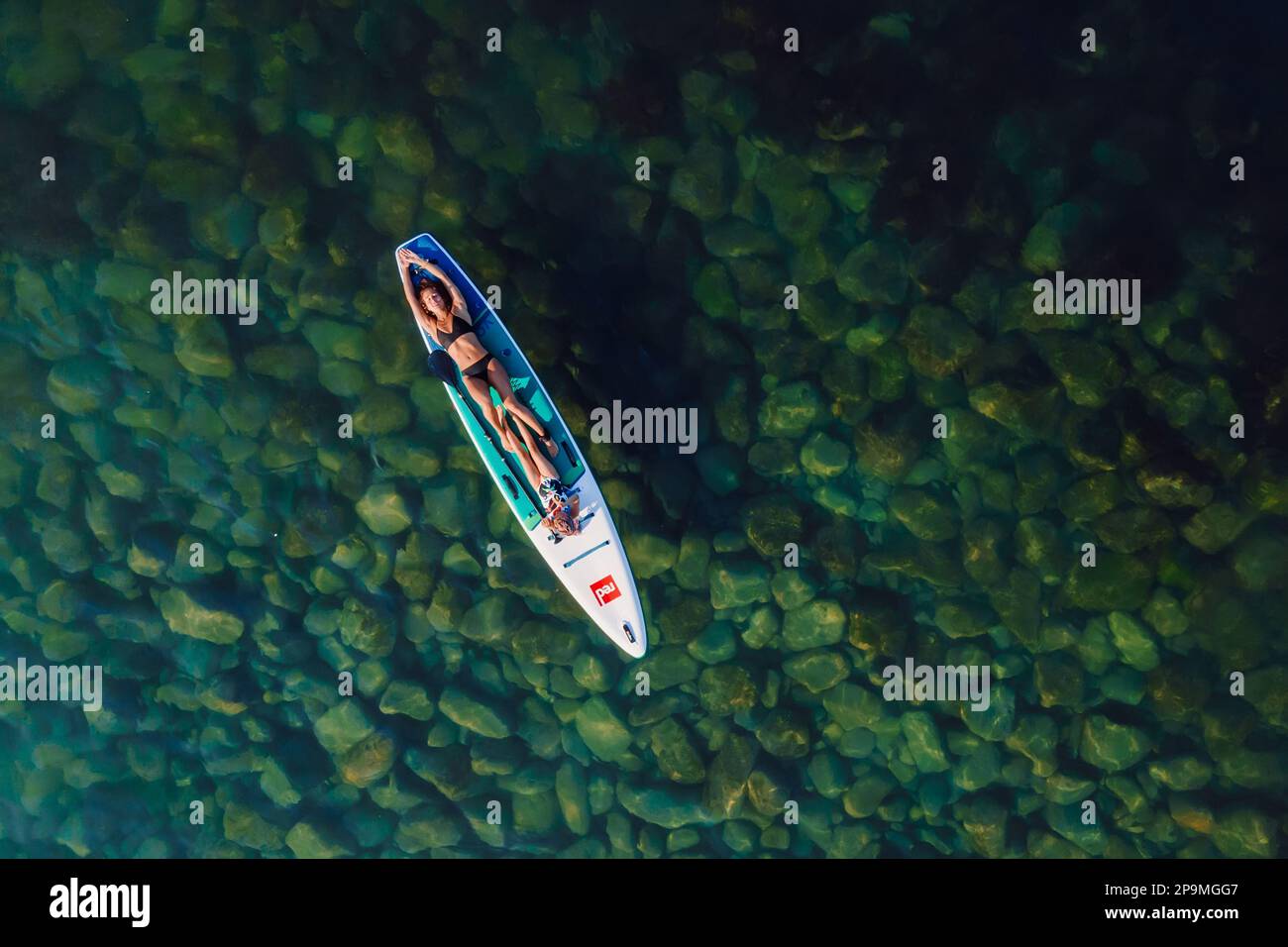 uly 24, 2022. Antalya, Turchia. Donna snella con bambino che si rilassa in piedi su paddle board in mare tranquillo. Donna con bambina su Red paddle SUP board i Foto Stock