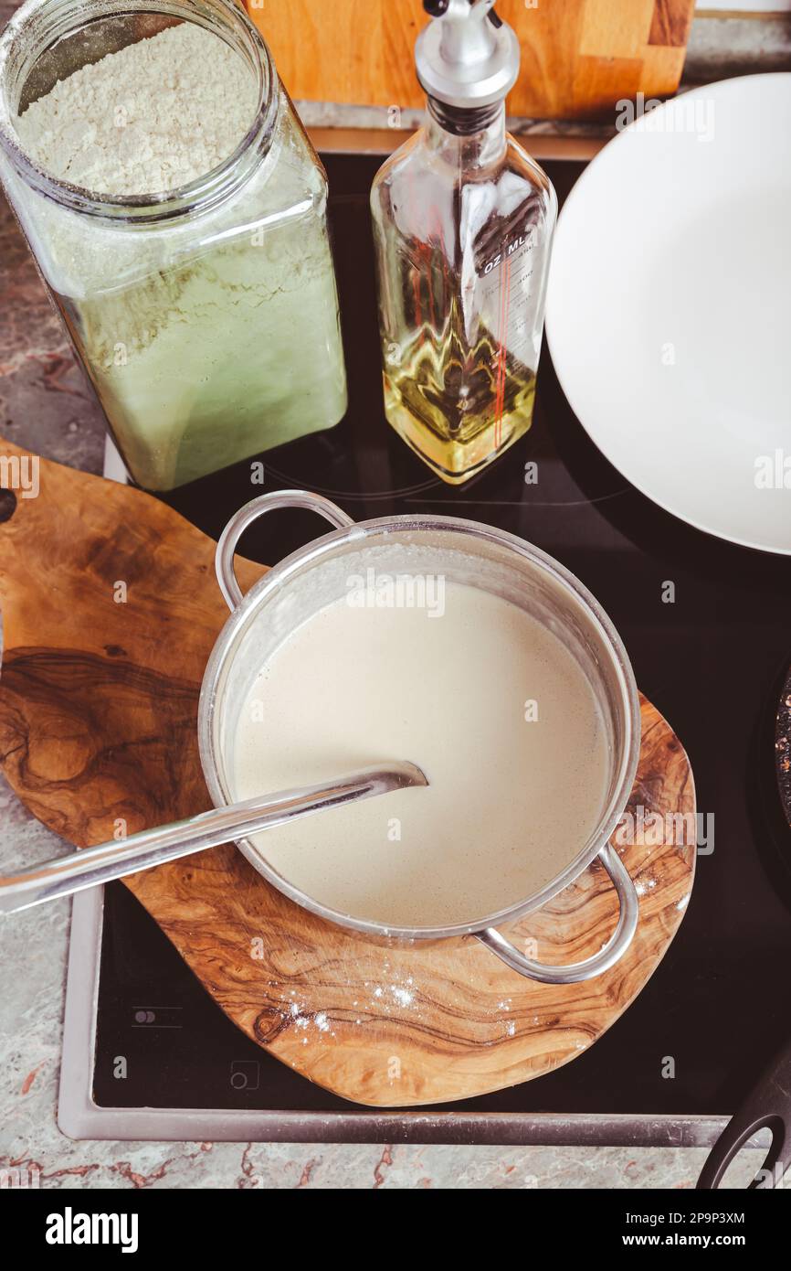 Preparazione di frittelle sottili in padella in cucina, con pasta da cucina per crepes e frittelle. Foto Stock
