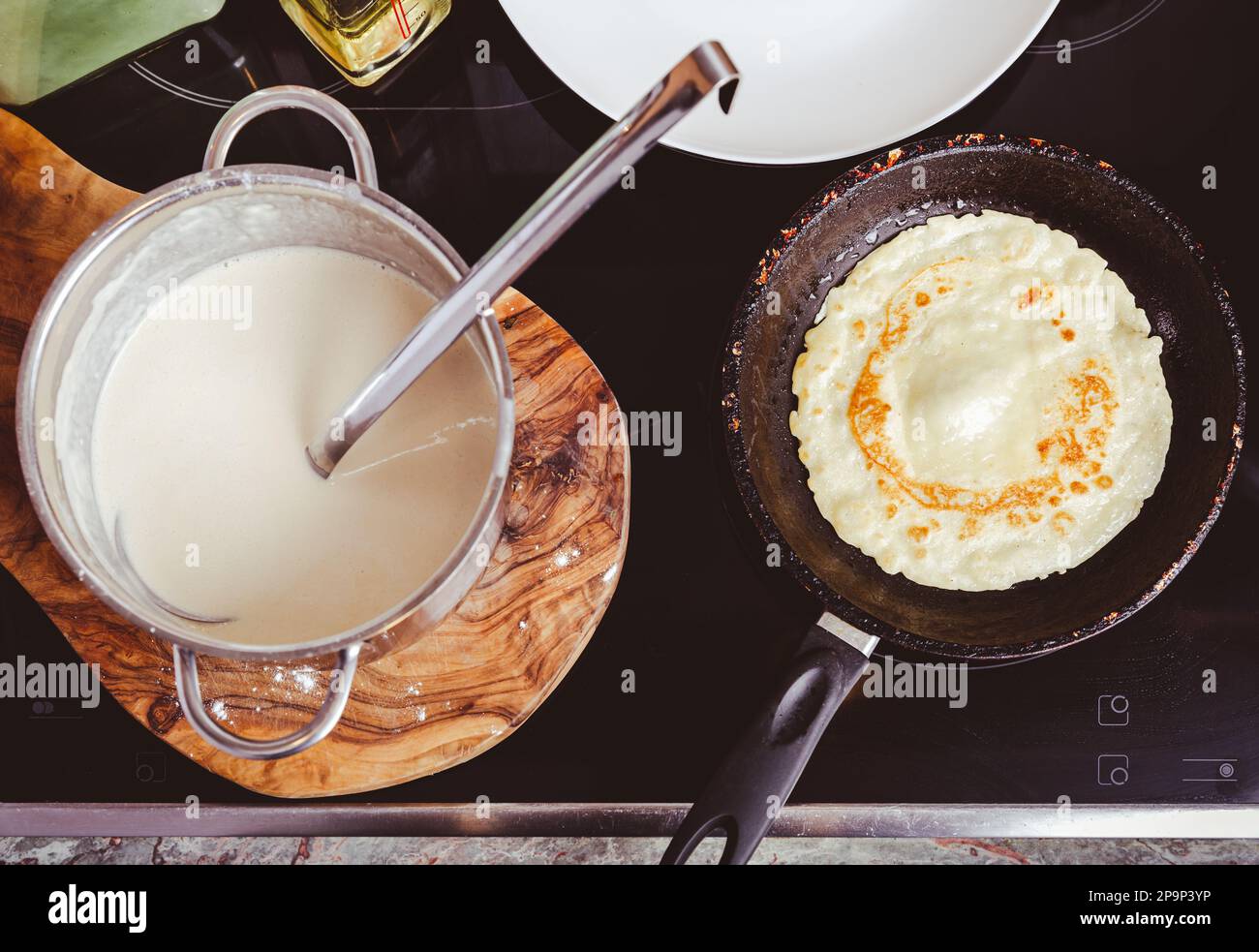 Preparazione di frittelle sottili in padella in cucina, con pasta da cucina per crepes e frittelle. Foto Stock