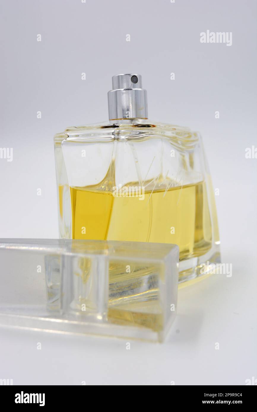 Profumo elegante da donna, una bottiglia di profumo in una bottiglia di vetro con un fresco aroma luminoso e liquido giallo si trova su uno sfondo bianco. Foto Stock