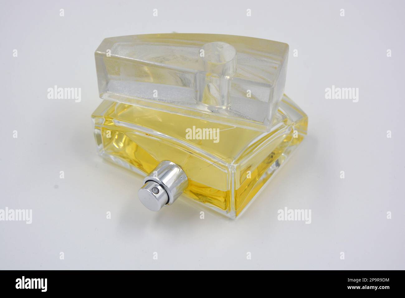 Profumo elegante da donna, una bottiglia di profumo in una bottiglia di vetro con un fresco aroma luminoso e liquido giallo si trova su uno sfondo bianco. Foto Stock