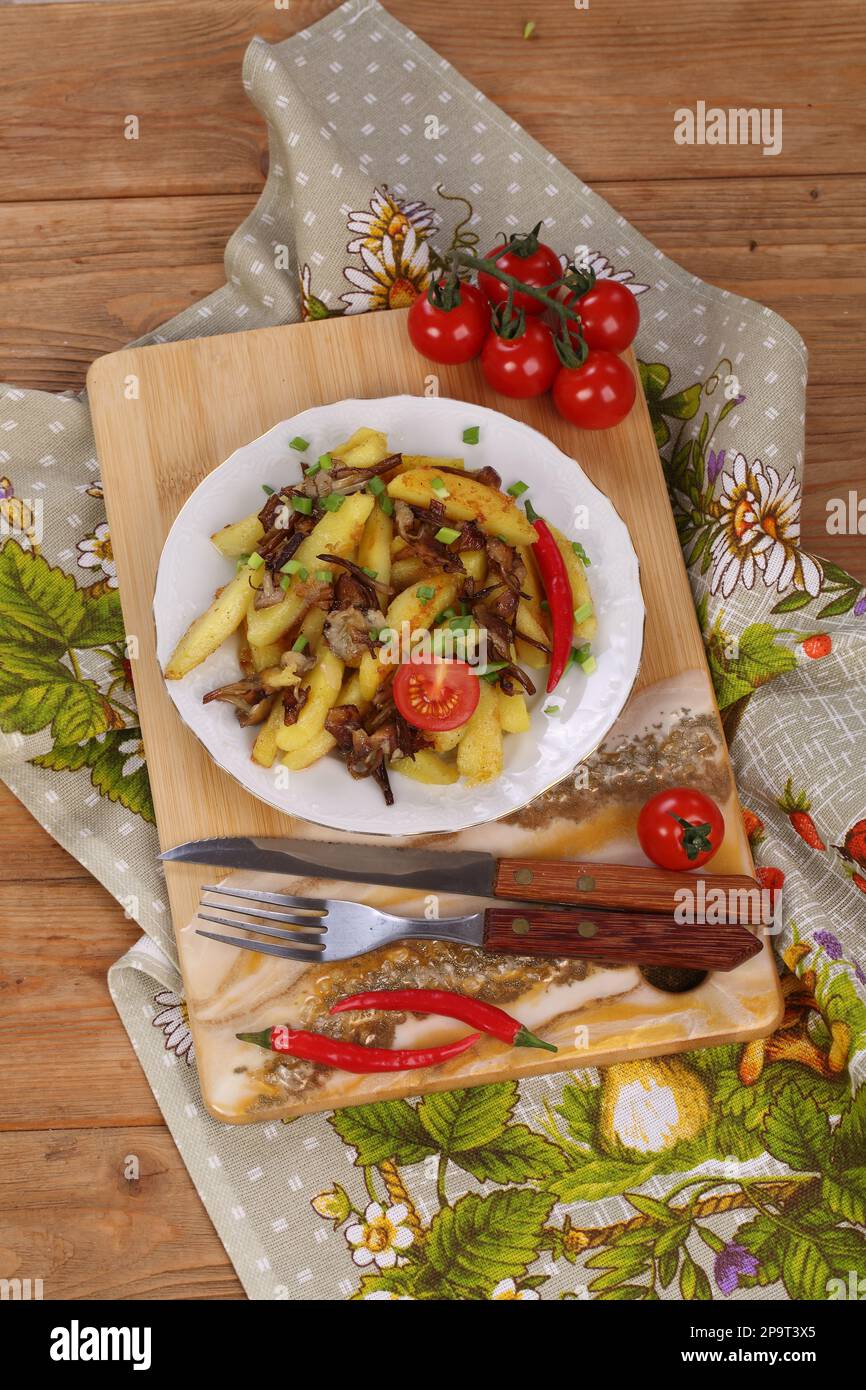 Patate fritte con funghi su fondo di legno Foto Stock