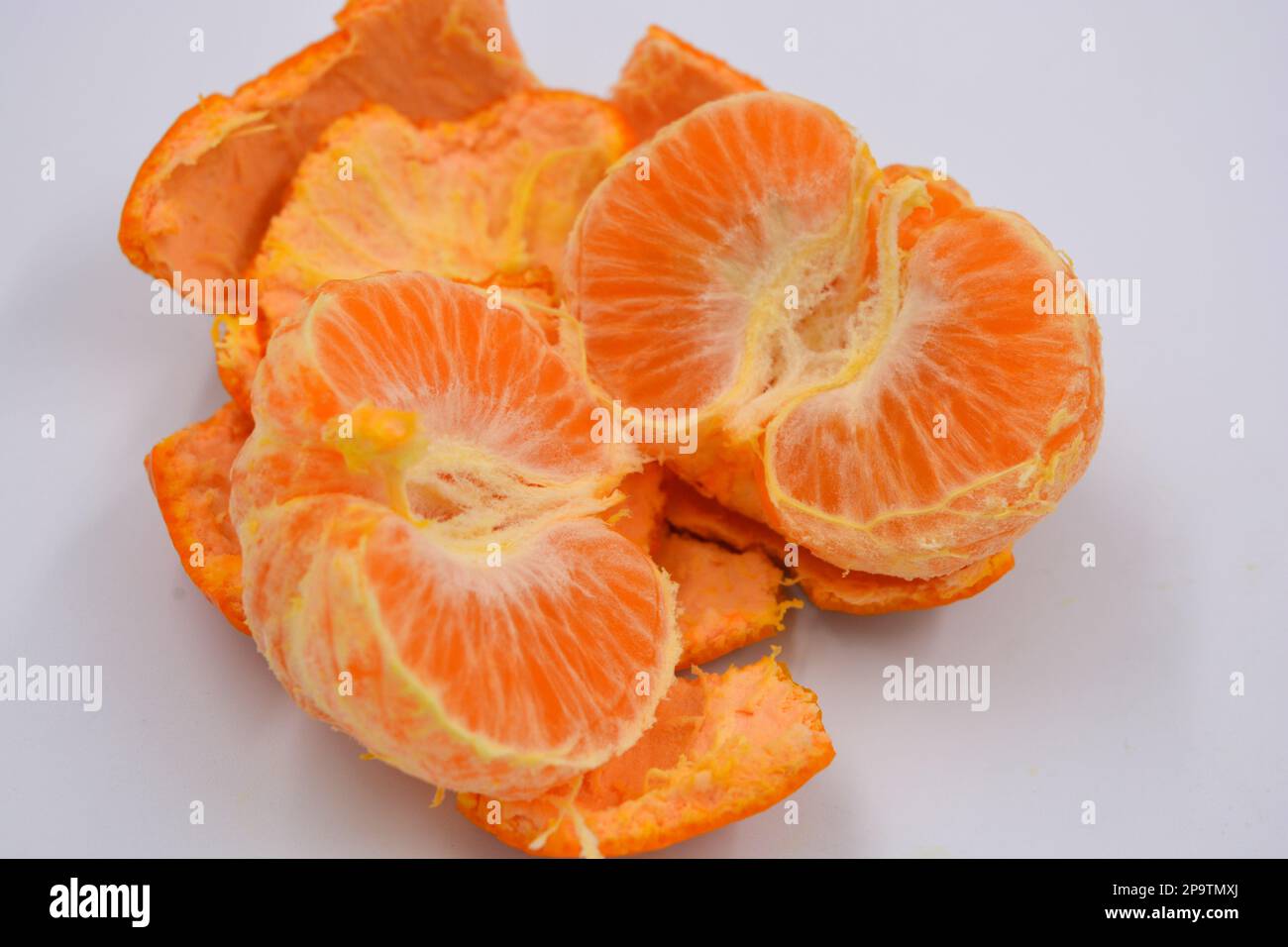 Frutta fresca, mandarino arancione con una buccia sottile rimossa si trova su uno sfondo bianco. Cibo sano, sano, stile di vita sano, vitamina giorno. Foto Stock