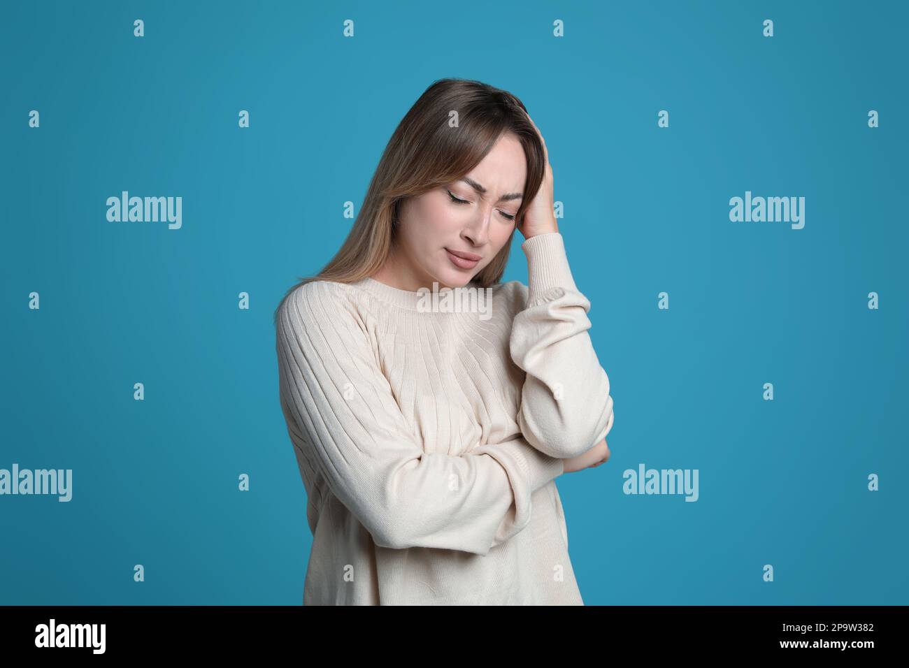 Giovane donna che soffre di mal di testa su sfondo azzurro Foto Stock