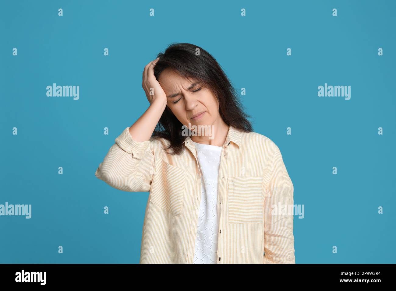Donna matura che soffre di mal di testa su sfondo azzurro Foto Stock
