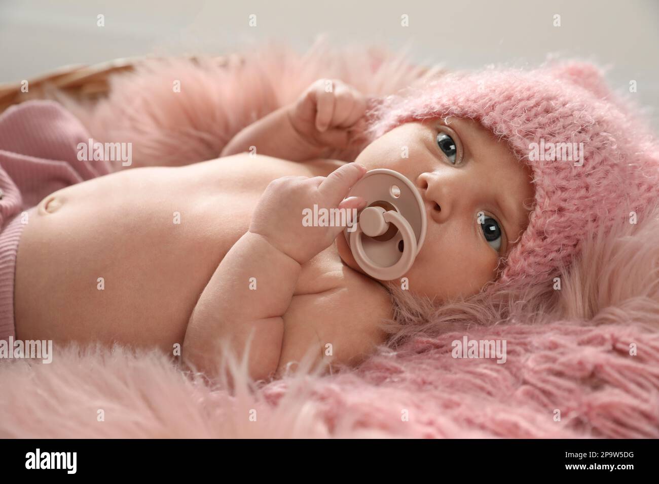 Adorabile neonato con succhietto nel cestello in vimini Foto Stock