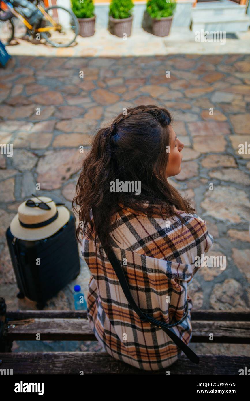 Una bellissima turista femminile è seduta su una panchina. Sta facendo una pausa Foto Stock
