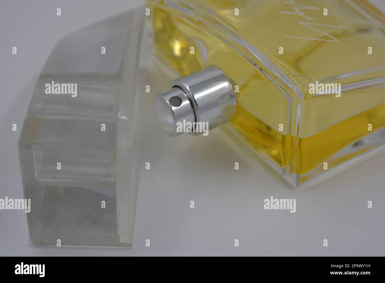 Profumo elegante da donna, una bottiglia di profumo in una bottiglia di vetro con un fresco aroma luminoso e liquido giallo si trova su uno sfondo bianco. Foto Stock