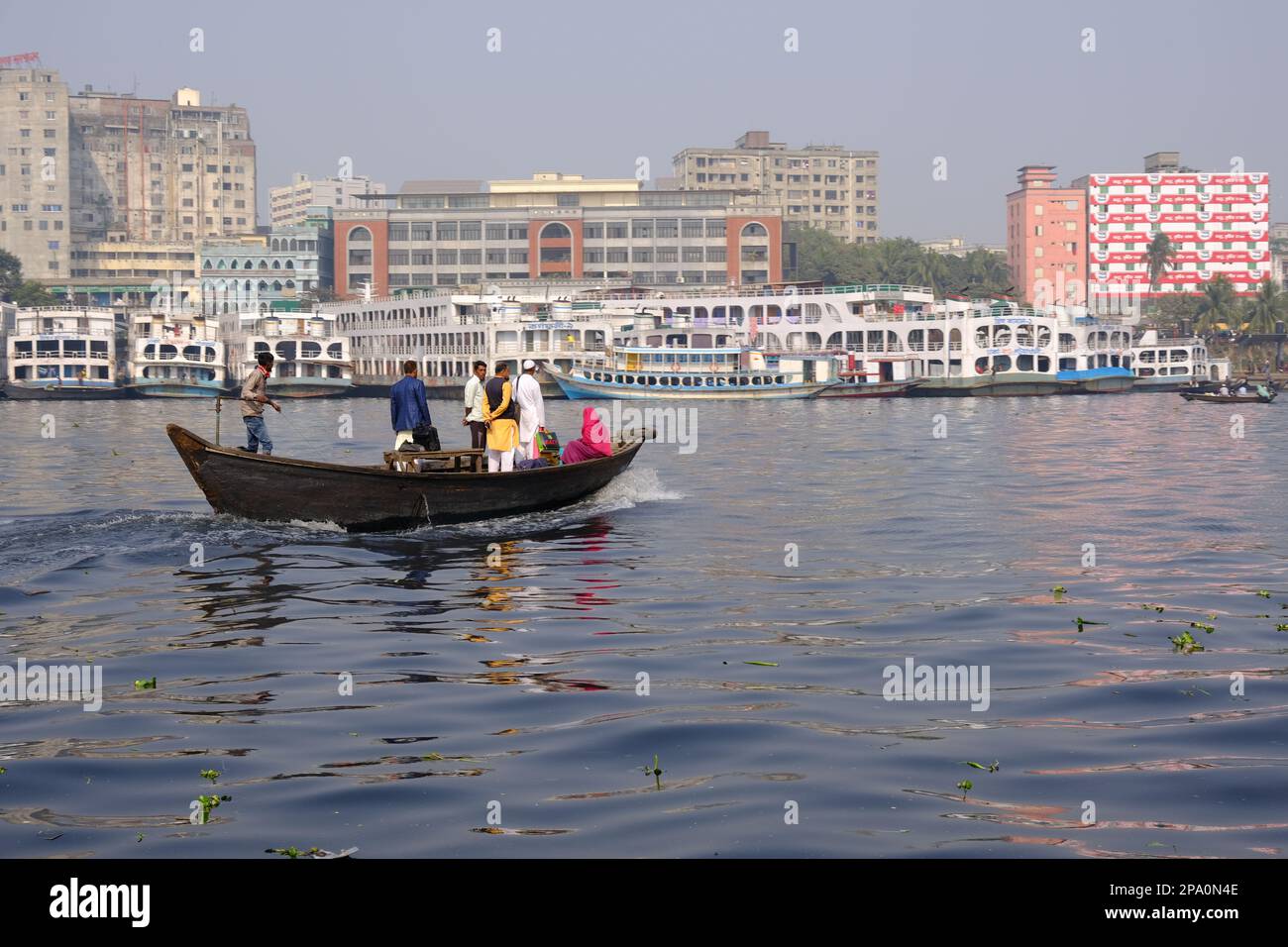 La gente attraversa il fiume Buriganga da Keraniganj a Sadarghat a Old Dhaka in barca a mano. Si vedono lanci ancorati al porto. Bangladesh Foto Stock