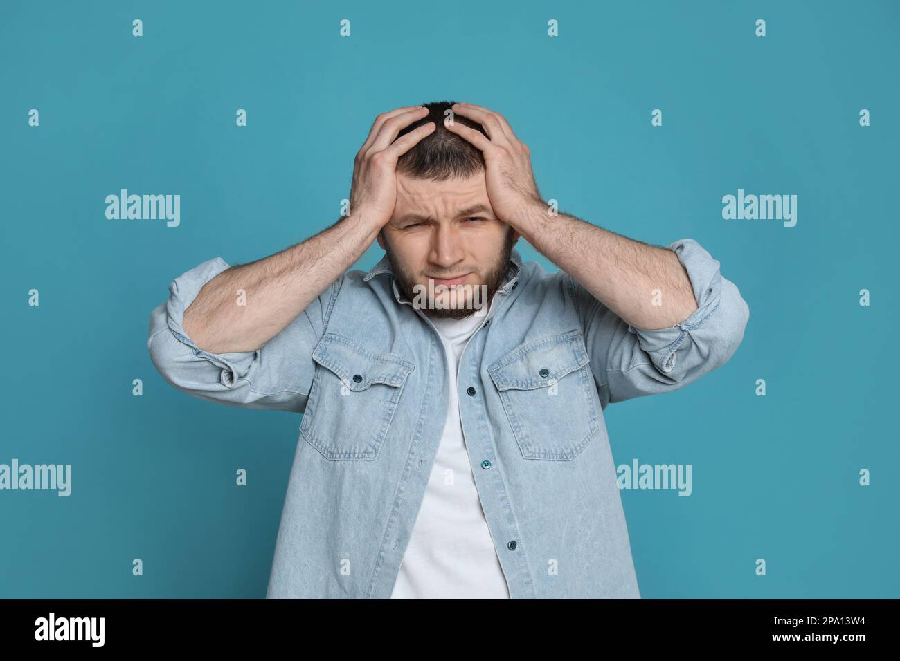 Uomo che soffre di mal di testa su sfondo azzurro Foto Stock