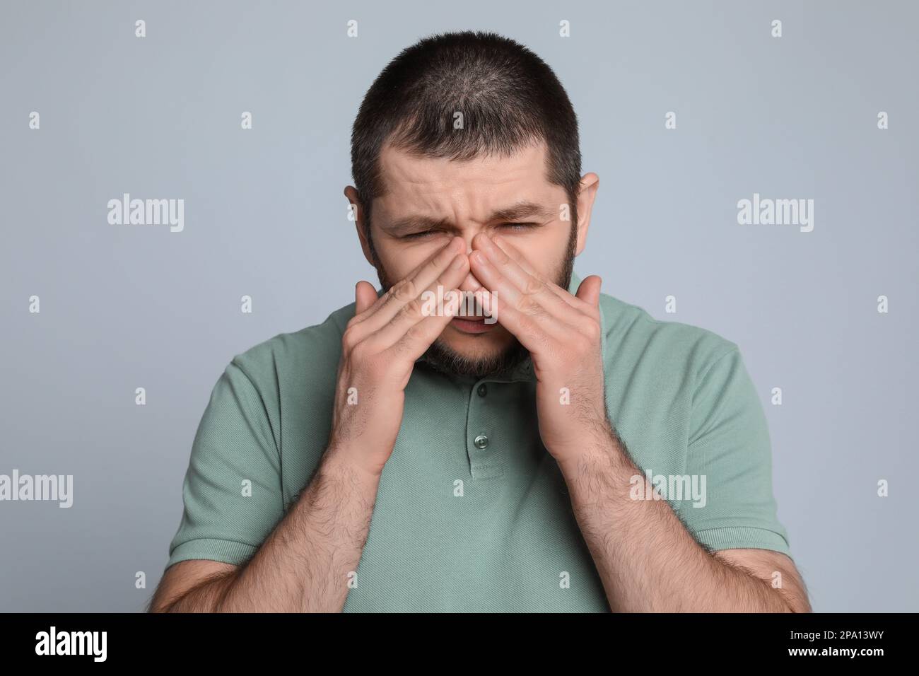 Uomo che soffre di mal di testa su sfondo grigio chiaro Foto Stock