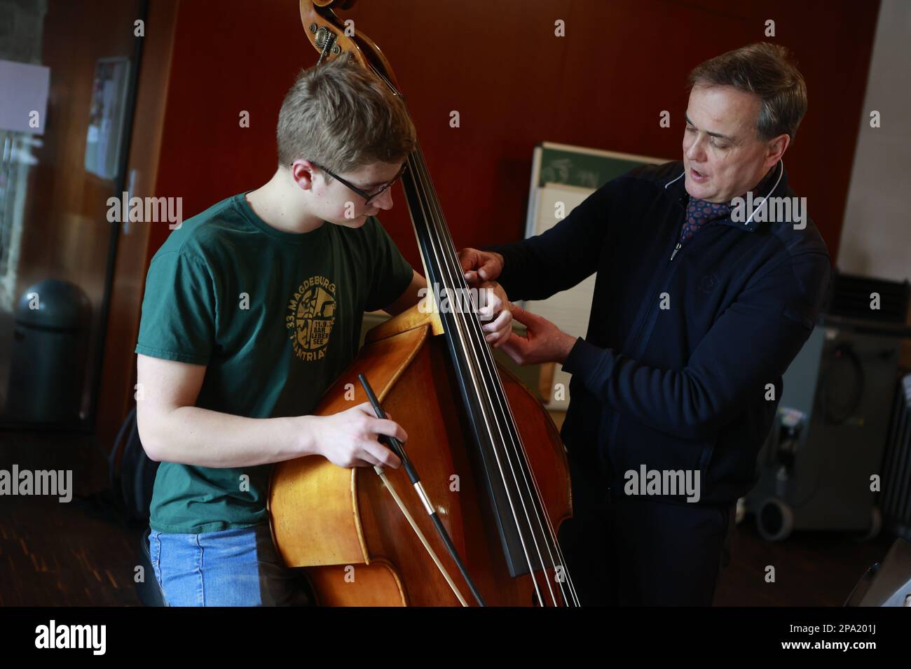 Blankenburg, Germania. 11th Mar, 2023. Il Professor Stephan Petzold offre consigli in lezioni private ai partecipanti al workshop "Double Bass" della Young Bass Academy presso il Monastero di Michaelstein. Il Junge Bass Akademie è un laboratorio per bambini e giovani entusiasti del basso provenienti da tutta la Germania per migliorare le loro capacità di gioco. Credit: Matthias Bein/dpa/ZB/dpa/Alamy Live News Foto Stock