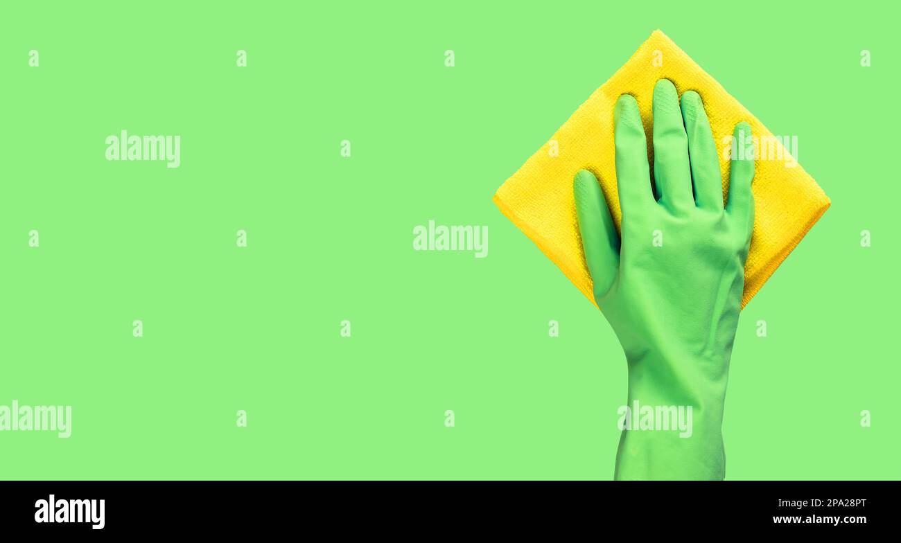 Mano nel guanto verde che tiene un panno in microfibra per la pulizia. Sfondo del banner con spazio di copia per il testo. Foto Stock