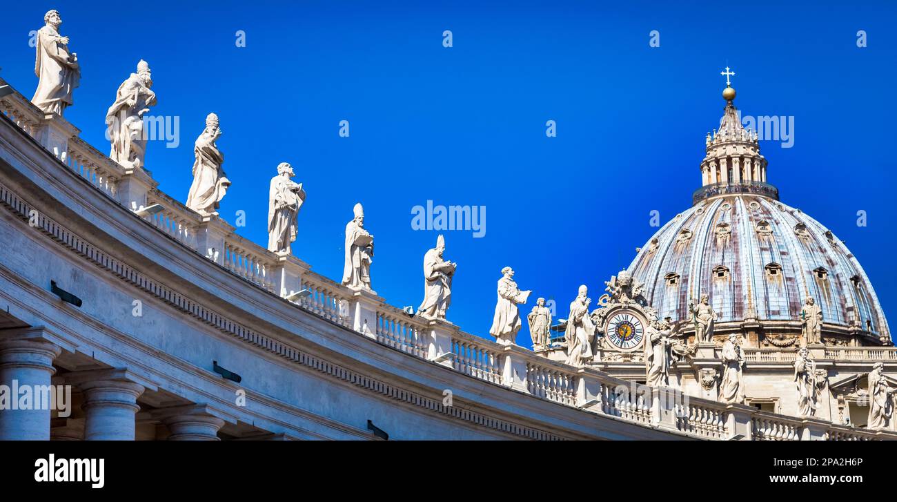 Statue di santi cattolici. Decorazioni sul colonnato Bernini, Cattedrale di San Pietro, con la cupola sullo sfondo - Roma, Italia Foto Stock