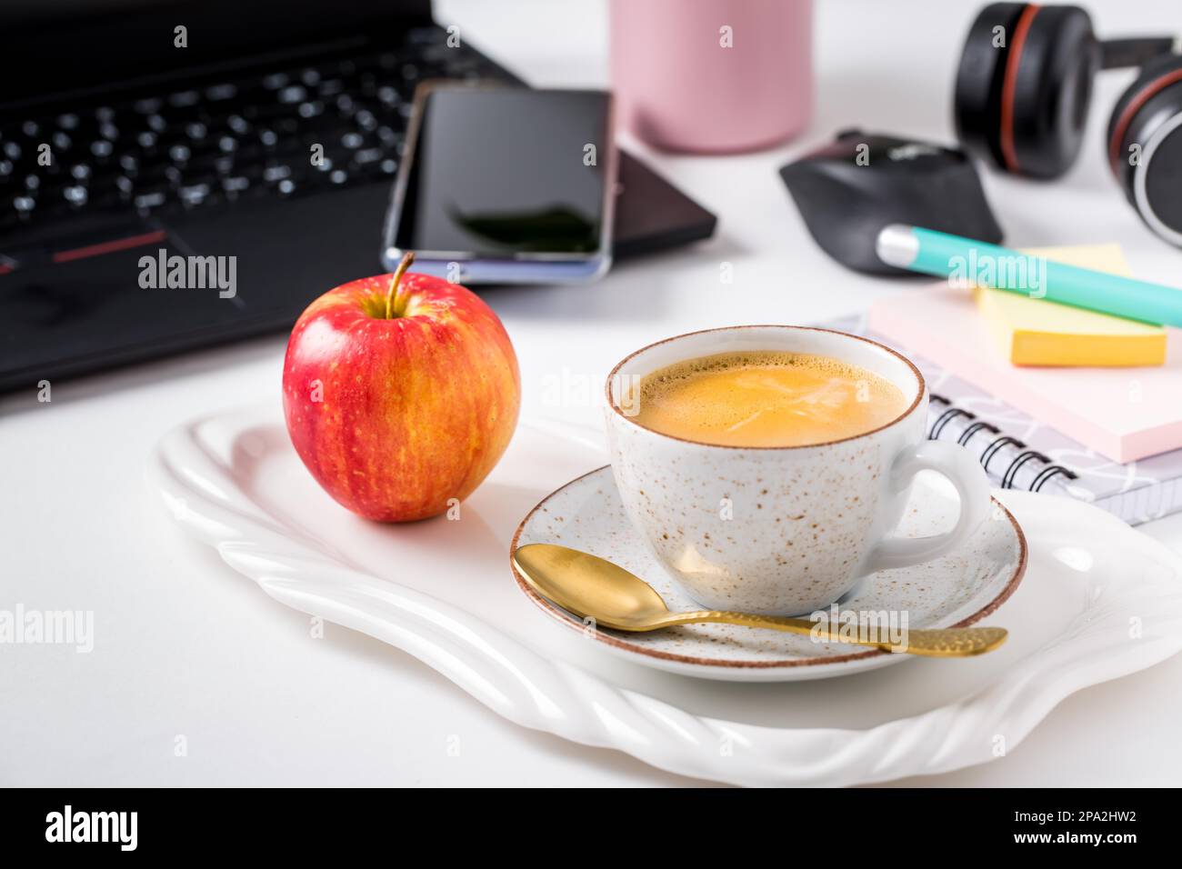 Posto di lavoro e scrivania con caffè, computer portatile, mela, cuffia e smarthpone. Piatto in tonalità nera Foto Stock