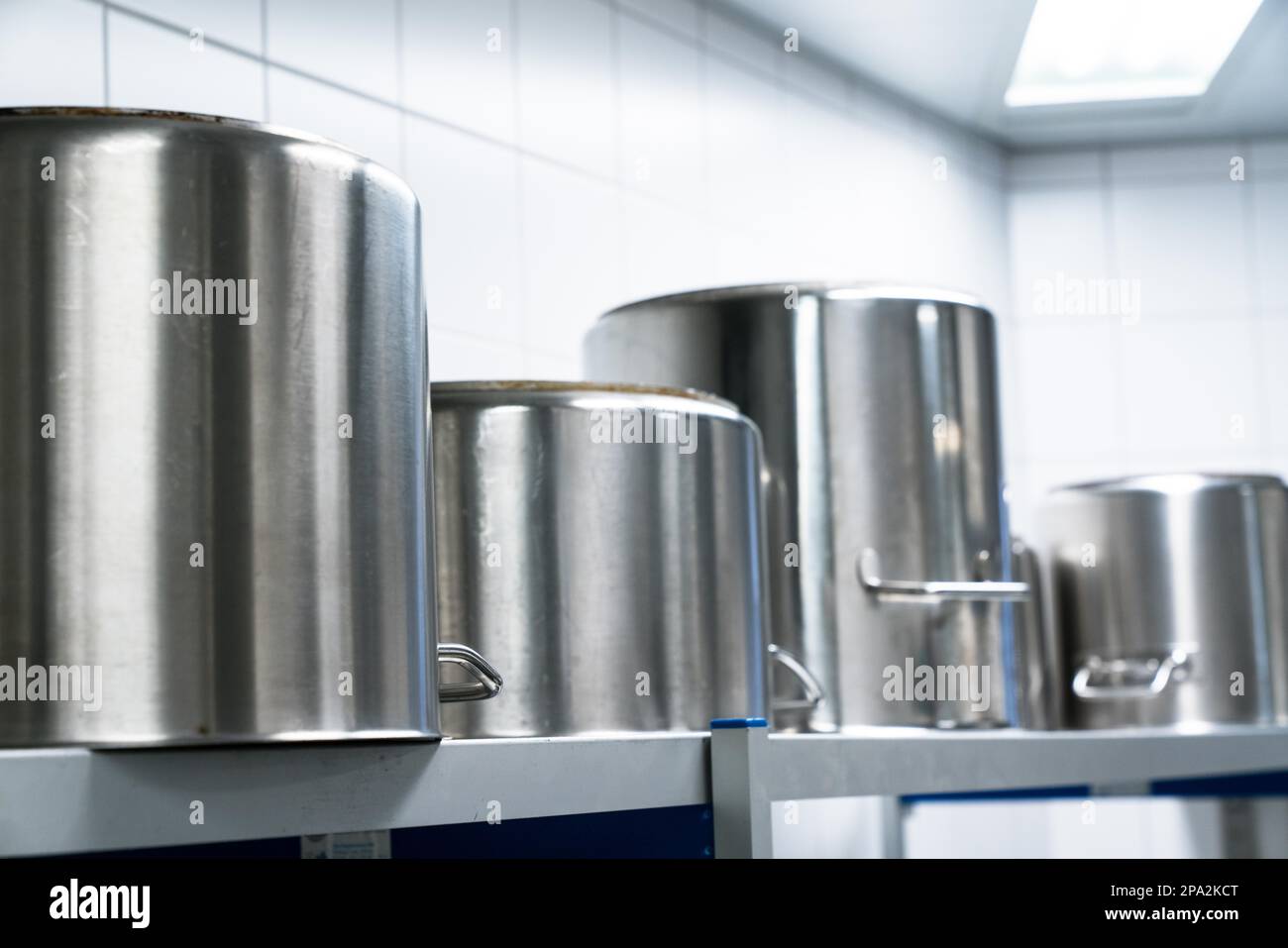 Fila di grandi pentole di metallo in un kithcen ristorante di dimensioni industriali su una mensola di metallo Foto Stock