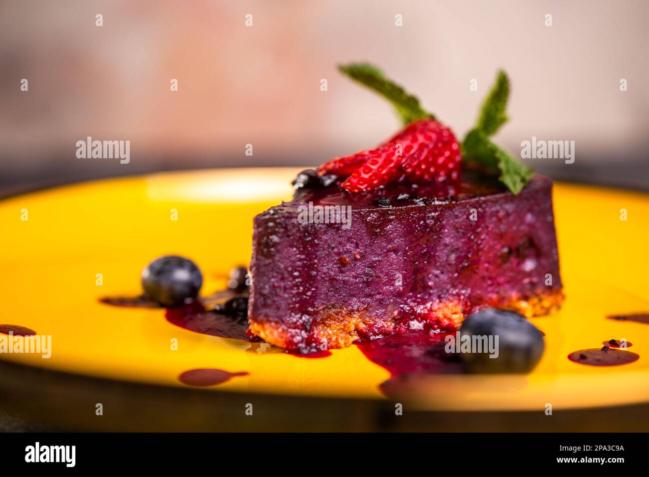 primo piano di mousse di frutti di bosco con fragole su un piatto giallo. Foto Stock