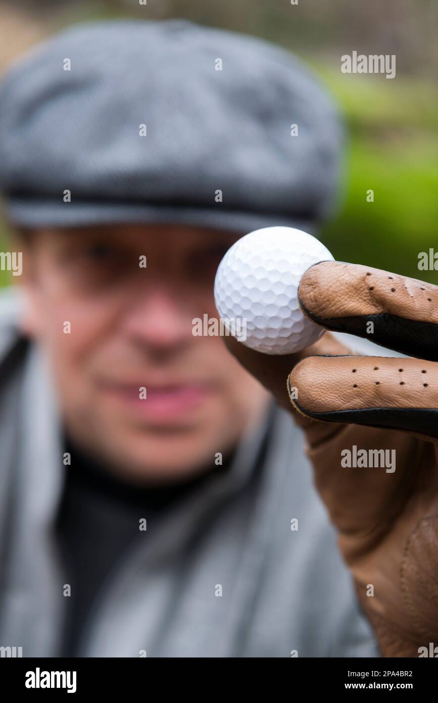 Elegante golfista con Cap che tiene una palla da golf in Svizzera. Foto Stock