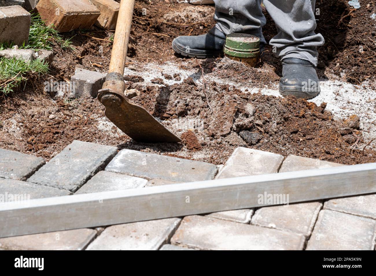 Brasiliano usando una zappa per preparare il suolo per posare blocchi di calcestruzzo. Foto Stock