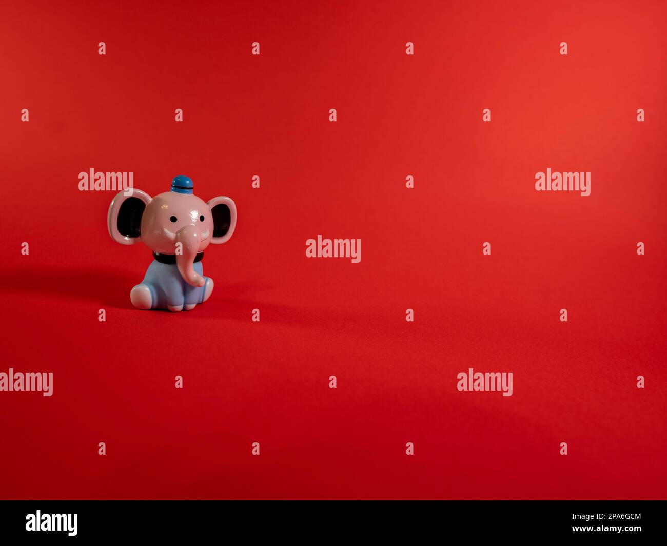 Una figurina di elefante su sfondo rosso con spazio di copia Foto Stock