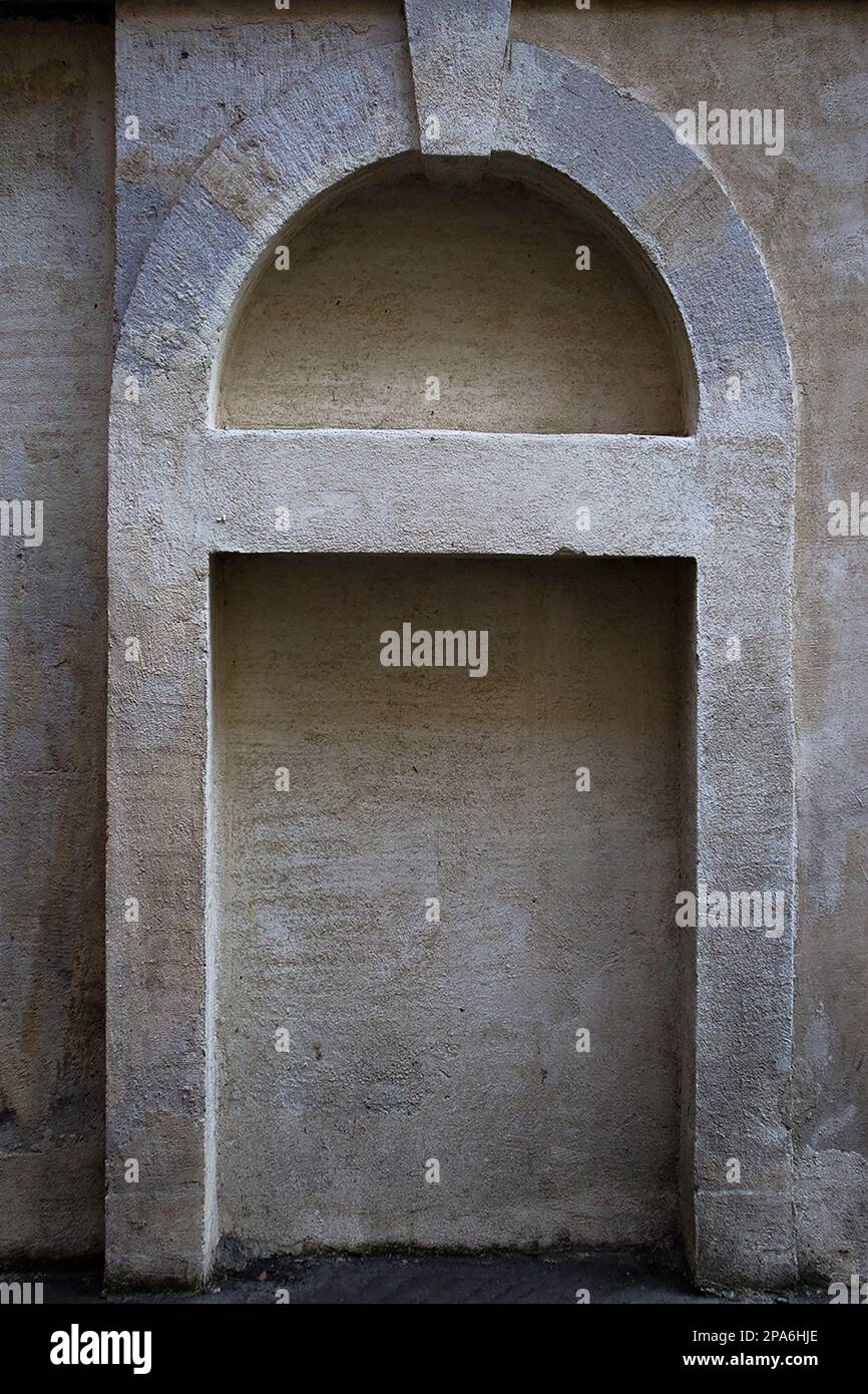 Una foto verticale di una nicchia in pietra ad arco situata su una parete d'angolo di una strada Foto Stock