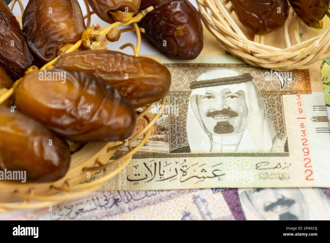 Primo piano delle date reali algerine su un piatto di legno. Arabia Saudita banconote di denaro. Concetto Ramadan. Foto Stock