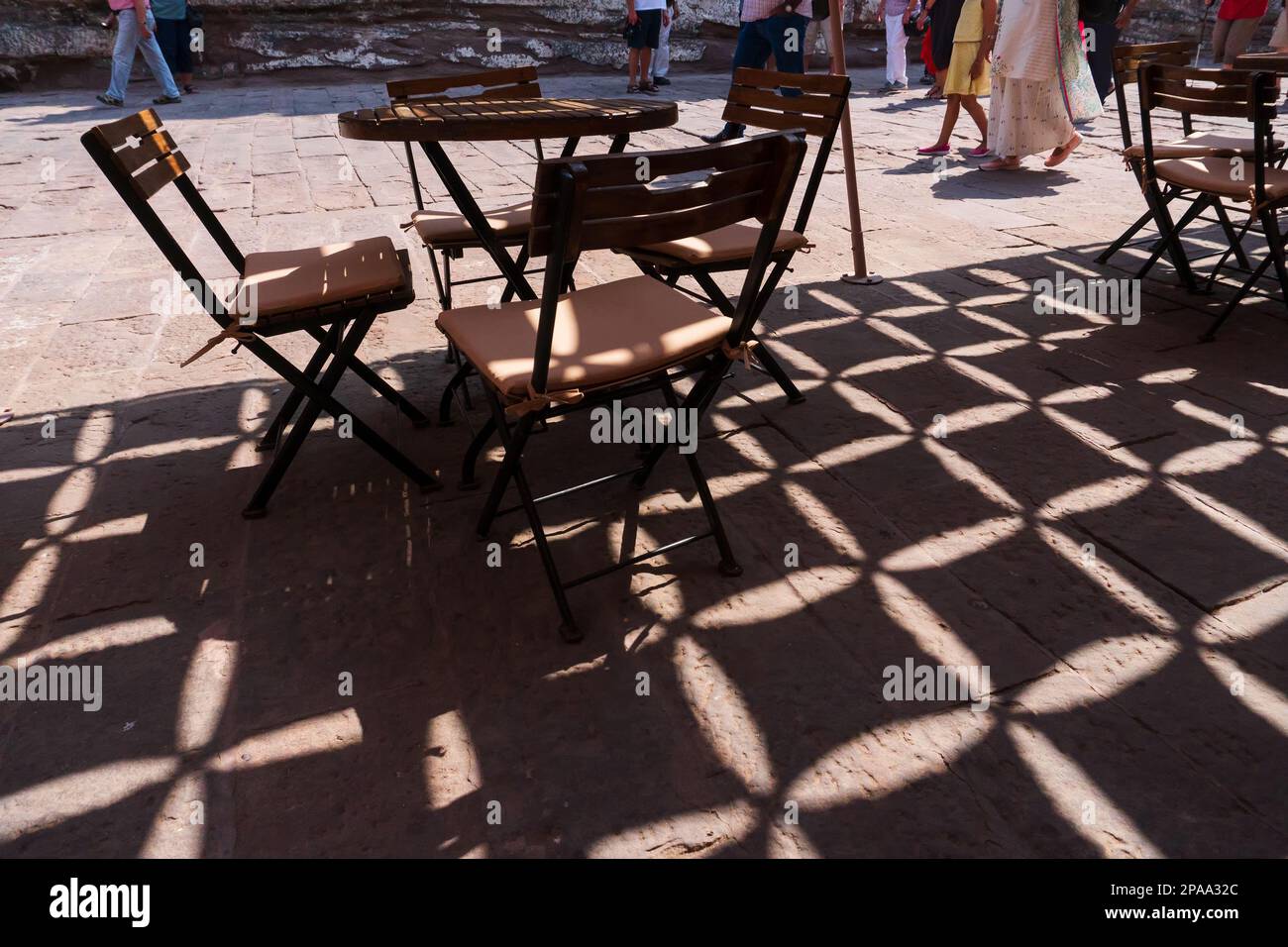 Gioco di luce e ombra, sedie e tavolo al ristorante del forte Mehrangarh, Jodhpur, Rajasthan, India. Il Forte di Mehrangarh è patrimonio dell'umanità dell'UNESCO Foto Stock