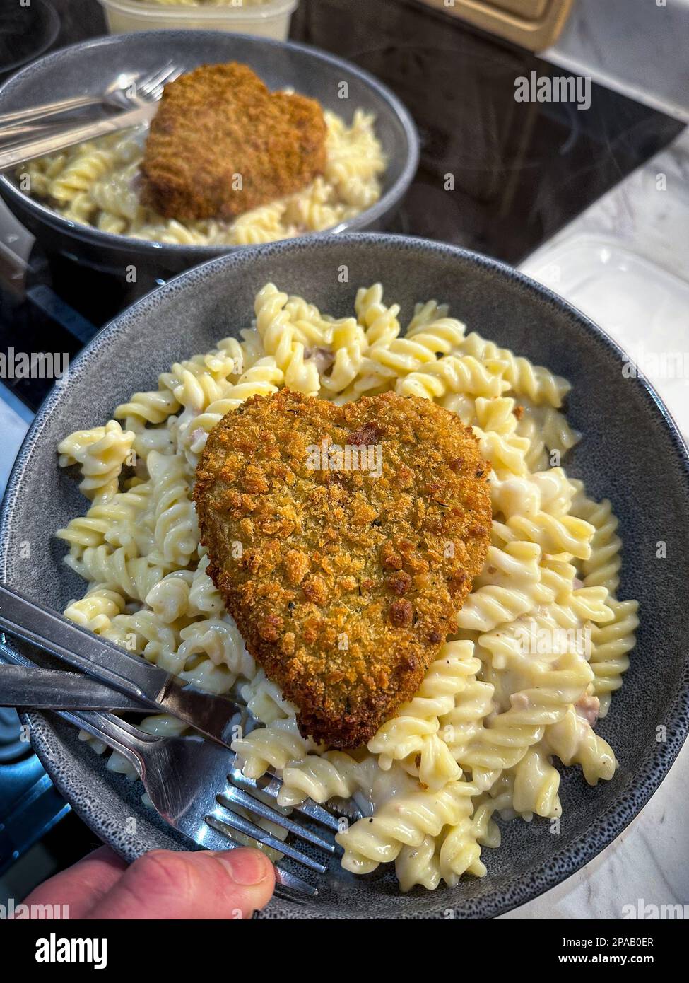 Alcuni carbonara fusilli pasta con un cuore d'amore crocchette a forma di cuore non ho potuto resistere a cucinare per me e la mia ragazza dopo alcuni giorni di sentirsi suicida a Foto Stock