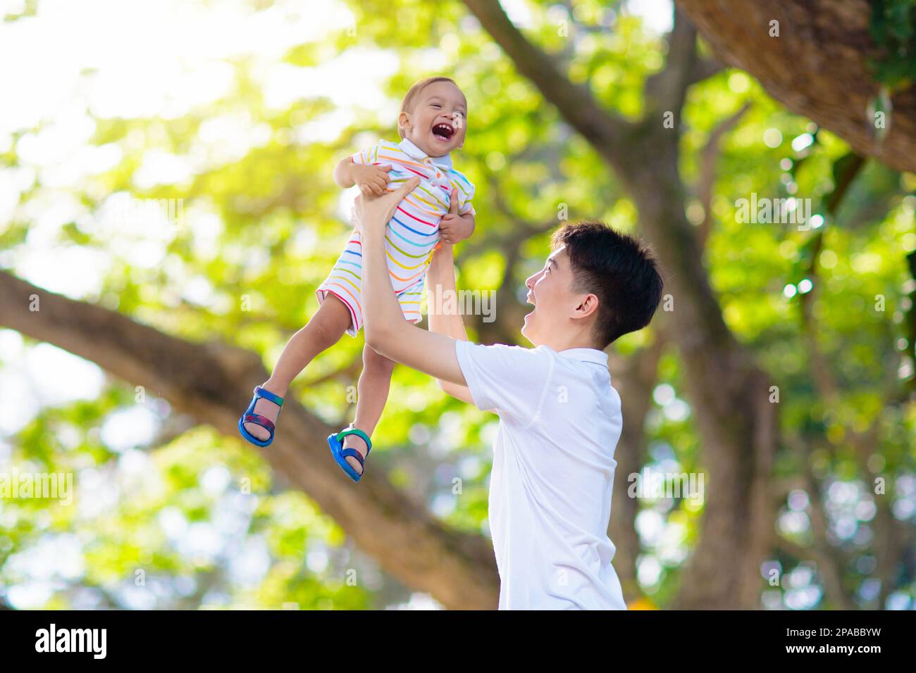 Ragazzo asiatico adolescente che gioca con suo fratello bambino. I fratelli si divertono nel parco estivo. Fratelli con grande differenza di età. Foto Stock