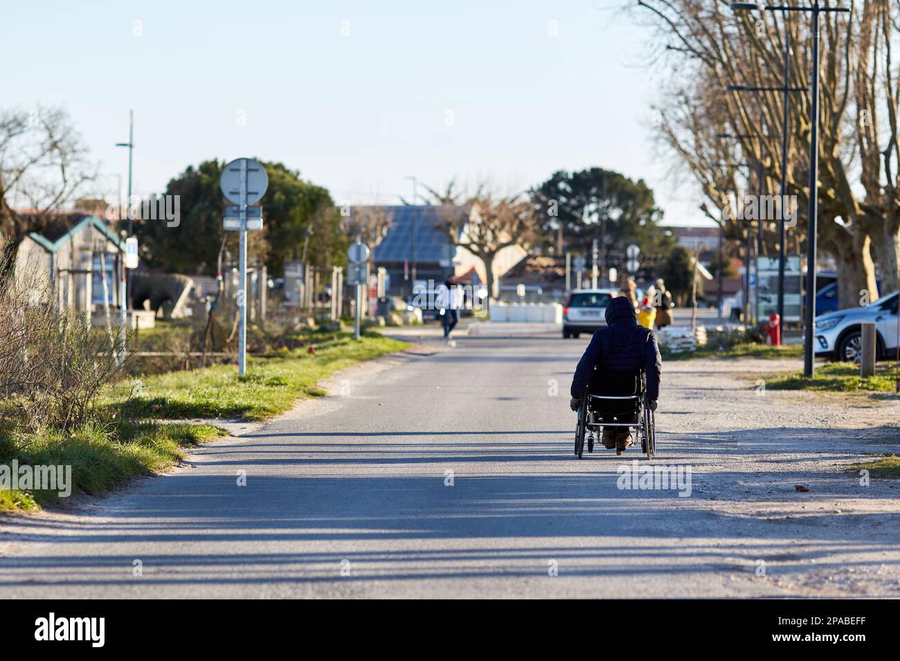 persona in carrozzina sulla strada una giornata di sole Foto Stock