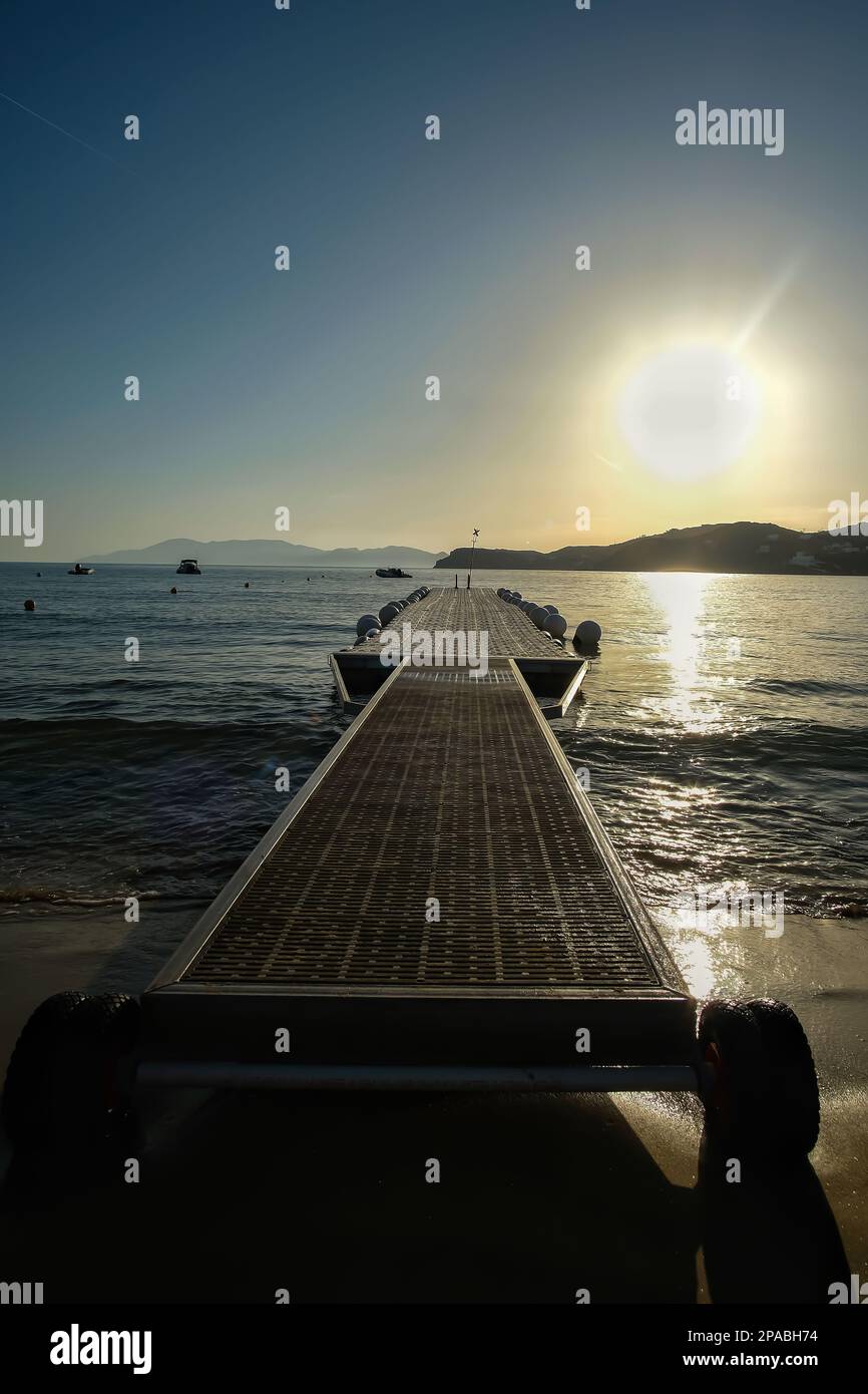 IOS, Grecia - 27 maggio 2021 : Vista di un molo galleggiante, noto anche come un ponte galleggiante alla spiaggia di Mylopotas in Grecia iOS al tramonto Foto Stock