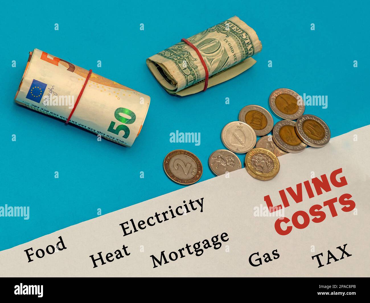 Banconote di carta moneta in diverse valute insieme con pila di monete accanto a un elenco di costo della vita spese su carta bianca Foto Stock