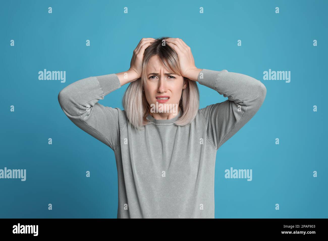 Donna che soffre di mal di testa su sfondo azzurro Foto Stock