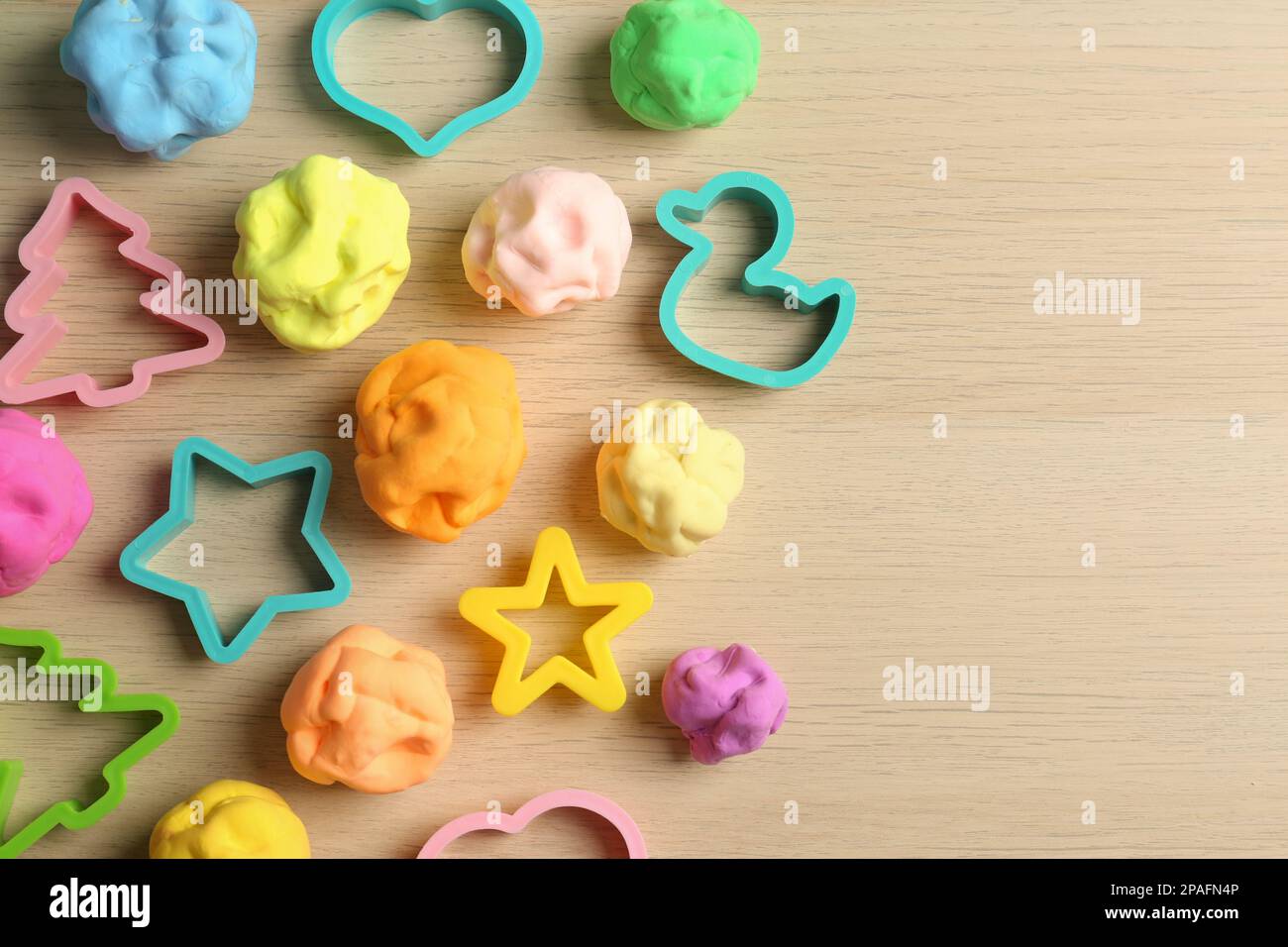 Pasta di colore diverso gioco con stampi su tavolo di legno, piatto. Spazio per il testo Foto Stock