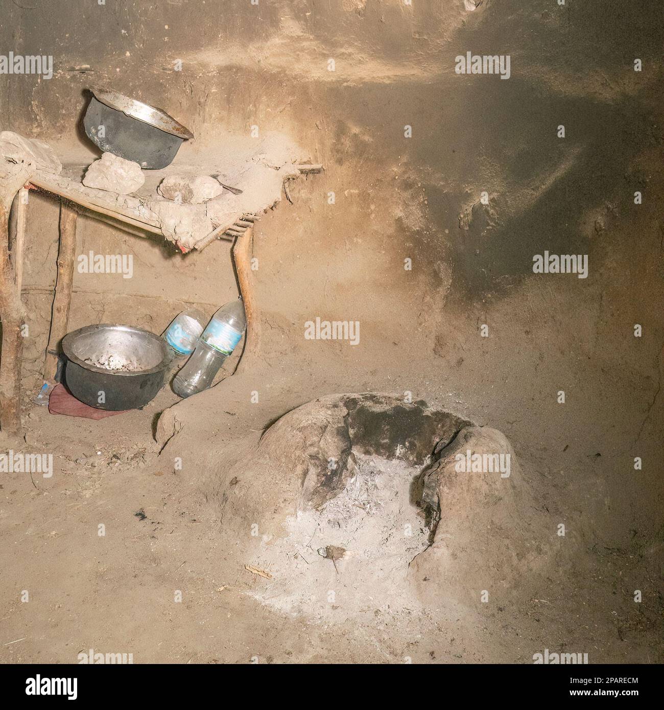 Uno spazio di cottura all'interno di una piccola capanna di fango masai, con un luogo di fuoco di fango e pentole bruciate. Foto Stock