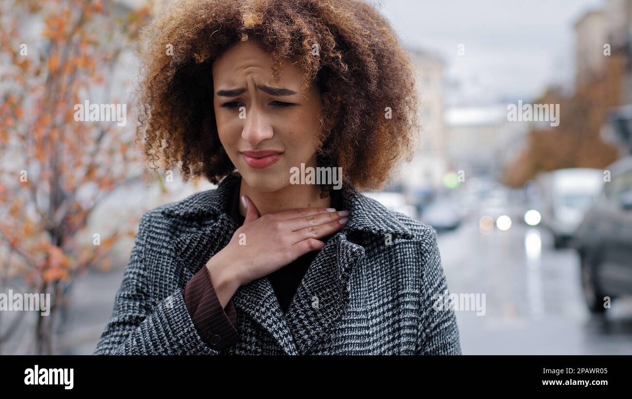 Ritratto afro americano che soffre di tonsillite angina in piedi all'aperto ritratto donna malsana toccare collo sente disagio sentimenti dolorosi Foto Stock