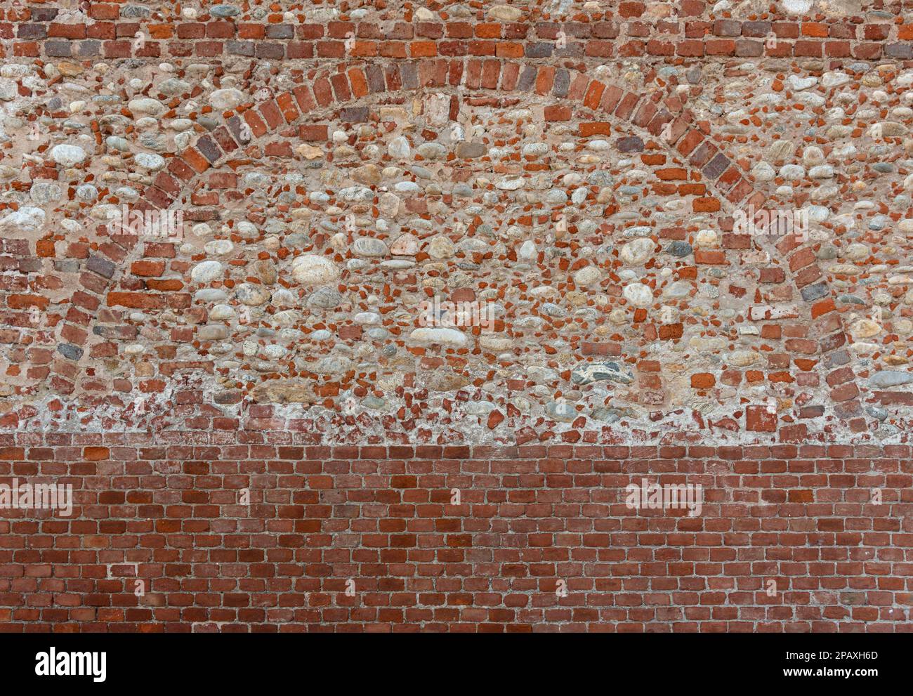 Struttura della parete con geometria con base in mattoni rossi, parete in mattoni e pietra con arco in mattoni rossi Foto Stock