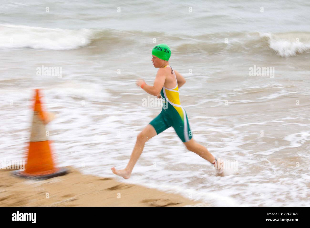 Il concorrente di ragazzo adolescente che sprinting fuori dell'acqua alle scuole nazionali Triathlon in Hervey Bay, Torquay, Queensland, Australia Foto Stock