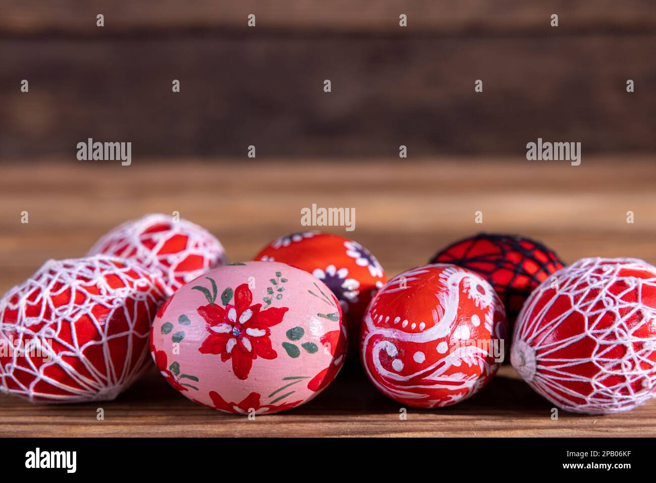 Uova di Pasqua in tonalità di rosso disposte in fila su vecchie tavole. Foto Stock