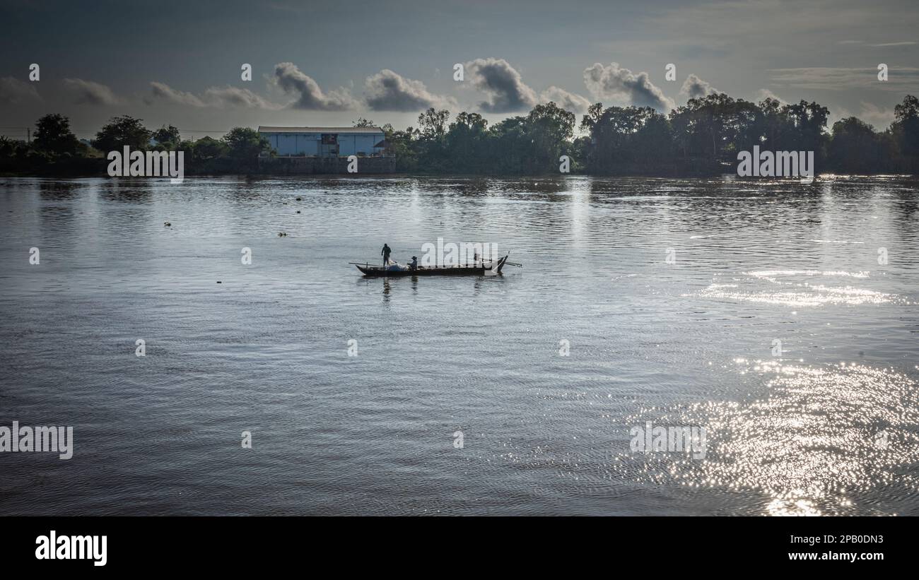 Due pescatori che lavorano sulla loro piccola imbarcazione tradizionale di legno sul fiume Mekong nella provincia di Kandal, Cambogia. Foto Stock