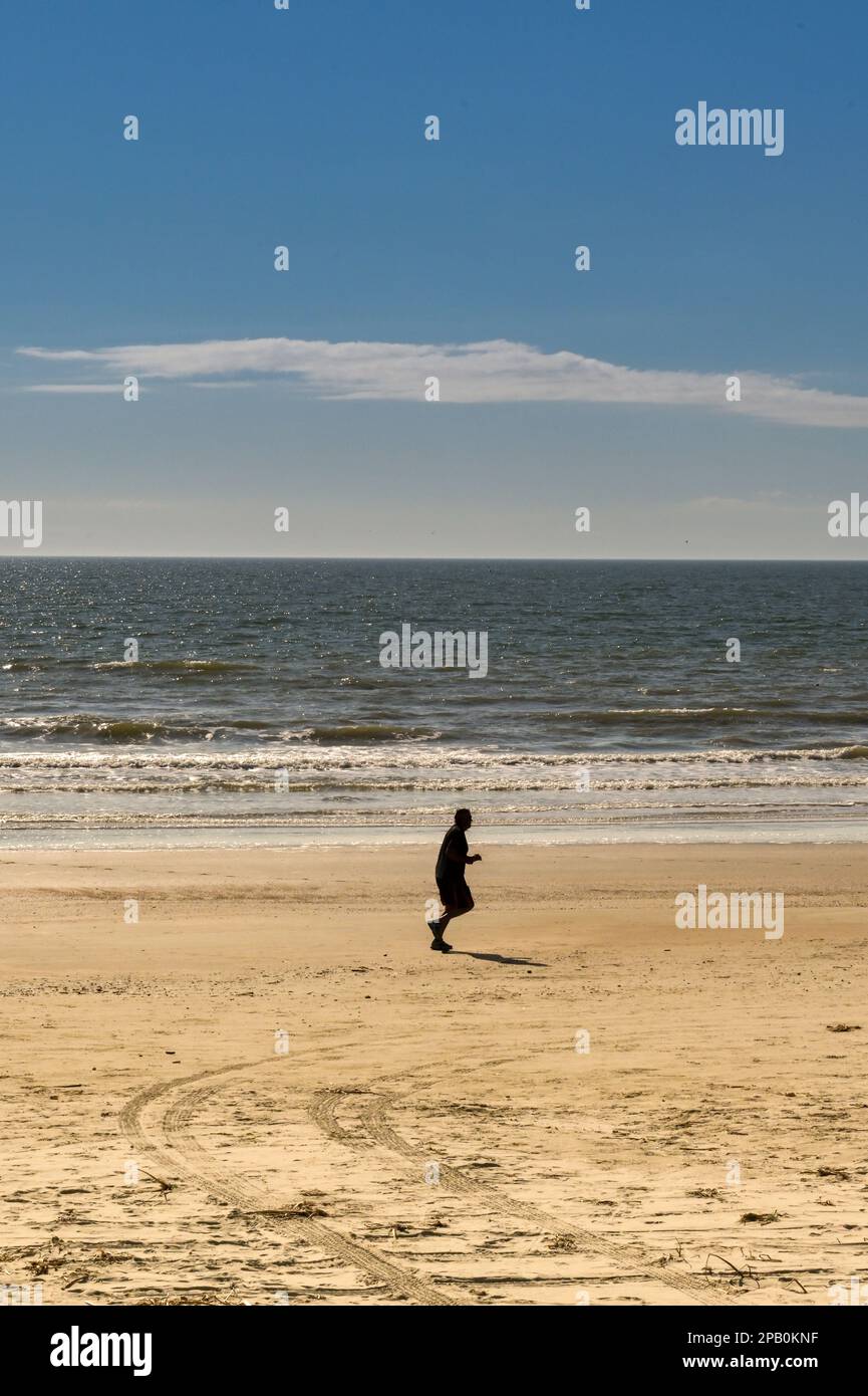 Galveston, Texas, USA - 2023 febbraio: Persona che fa jogging sulla spiaggia con la bassa marea Foto Stock
